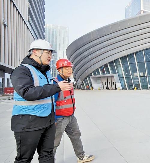 近日,在雄安国贸中心及京雄快线项目现场,雄商置业公司工程管理部工作人员许文康(左)与施工人员进行早班交流。 本报记者 曹铮摄