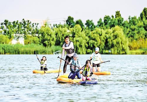 7月27日，雄安中央绿谷，孩子们在教练指导下体验桨板运动。