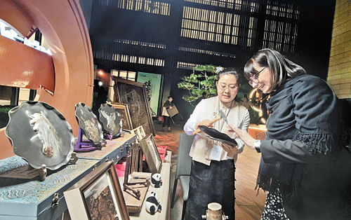 10月24日晚，“雄安之约”河北特色非遗展示活动在2026全球治理论坛（雄安）会场外举行。图为河北省级非遗代表性项目郭氏铁板浮雕代表性传承人郭墨涵（左）向外宾介绍非遗作品。本报记者 王 伟摄